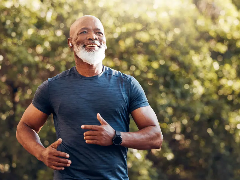 Smiling grey-bearded man jogging outdoors