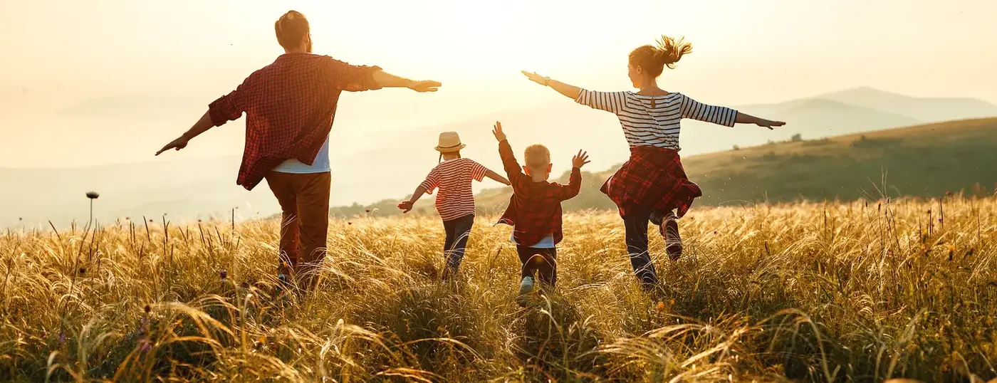Family running through a field at sunset